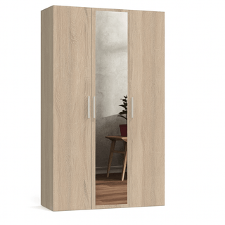 The CHOICEWARDROBE Ferrano 3 Door Wardrobe in Oak with Mirror (120cm) features vertical silver handles and a central full-length mirror, reflecting a chair, plant, and part of the room wall.