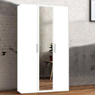 The CHOICEWARDROBE Ferrano 3 Door Wardrobe – White with Mirror (120cm) stands against a white brick wall, its silver handles and central full-length mirror reflecting a plant and part of a wooden chair on the wooden floor.