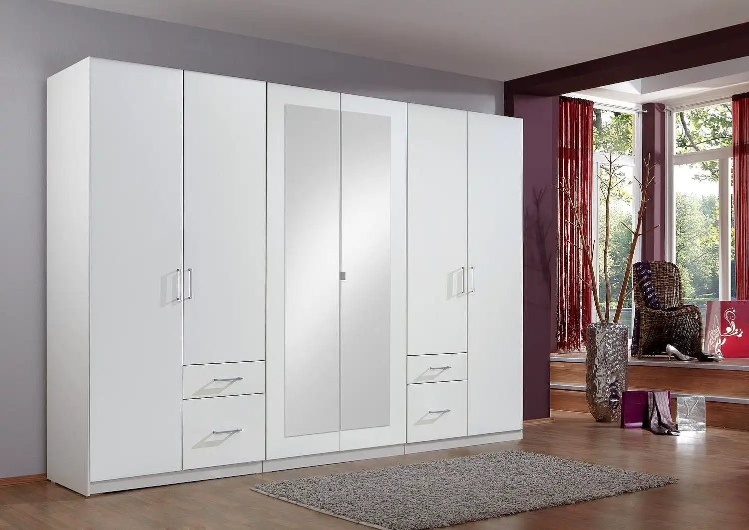 White hinged wardrobe with 6 doors and mirrored centre doors, featuring metal handles and drawers.