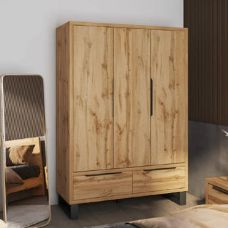 A CHOICEWARDROBE Hamburg 3 Door Wooden Wardrobe in Wotan Oak finish with 2 drawers and black metal legs stands in a modern bedroom next to a tall mirror reflecting part of the bed.