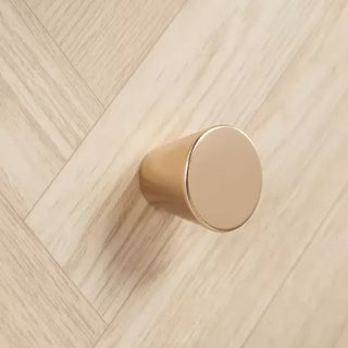 A round, gold cabinet knob is fixed to a light oak chevron surface, complementing the CHOICEWARDROBE Helena 3 Door Mirrored Wardrobe with oak chevron finish and wooden legs in the room.