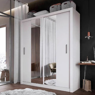 The CHOICEWARDROBE Ionia 180cm White Gloss Sliding Wardrobe with 2 mirror doors and a matt frame stands in the room. Four storage baskets are on top, a desk with a lamp is nearby, and large curtained windows add brightness and style.