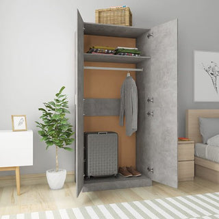 The CHOICEWARDROBE Kaylor 2 Door Wardrobe in a concrete effect finish opens to show folded clothes, a hanging striped shirt, a suitcase below, and a basket above—perfectly complementing modern bedroom decor.