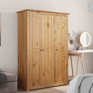 The CHOICEWARDROBE Kendal 80cm Solid Pine 3 Door Wardrobe with a natural wood finish and classic panel design stands by a desk with a round mirror and decorative items, creating a cozy bedroom atmosphere.