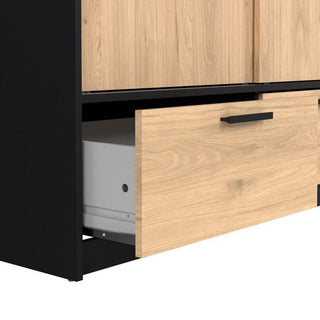 A close-up of a partially opened wooden drawer with a black handle in the CHOICEWARDROBE Liston 2 Door Sliding Wardrobe (Black & Oak Finish, 2 Drawers), revealing a white object and highlighting its sleek, modern design.