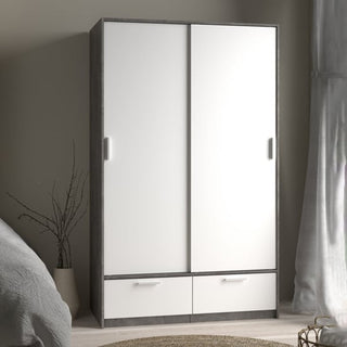 The CHOICEWARDROBE Liston 2 Door Sliding Wardrobe, featuring a concrete effect frame, white panels, and two lower drawers, stands against a neutral bedroom wall near a bed and sheer curtained window.