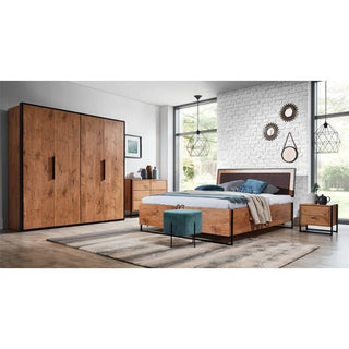 A modern bedroom includes the CHOICEWARDROBE Logan 204cm 2 Door Folding Wardrobe in Lancelot Oak with black accents, a double bed with blue bedding, a wooden nightstand, patterned rug, decorative mirrors on white brick walls, and large windows for natural light.
