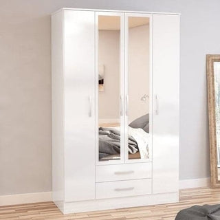 The CHOICEWARDROBE Lynn 4 Door Mirrored Wardrobe in white high gloss stands against a light wall, featuring two central mirrored doors, side solid doors, and two drawers below for modern storage. A mirror leans nearby on the wooden floor.