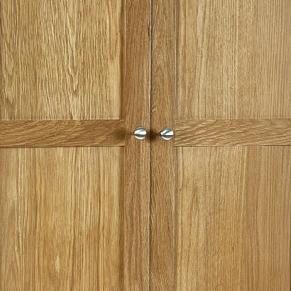 Close-up of the CHOICEWARDROBE Macon 2 Door Solid Oak Wardrobe in a natural finish, featuring classic paneled doors with round silver knobs—a premium storage solution with drawer and timeless bedroom style.
