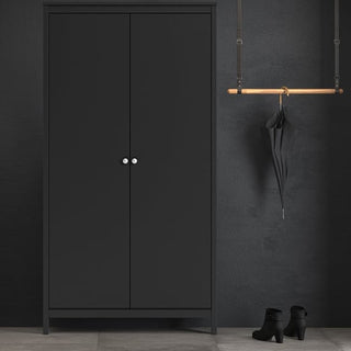 The CHOICEWARDROBE Macron 2 Door Wooden Wardrobe in matt black stands against a dark wall. To the right, an umbrella hangs from a wooden rack above a pair of black ankle boots on the floor.