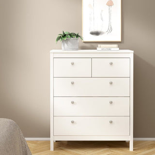 The CHOICEWARDROBE Macron 3 Piece Bedroom Furniture Set in white, featuring a 2 door wardrobe, 5 drawer chest, and bedside table in a classic minimalist design, stands against a beige wall with modern décor accents.