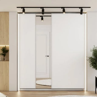 Minimalist room featuring the CHOICEWARDROBE Madrid 170 cm 2 Door Sliding Mirrored Wardrobe in matt white, light wood flooring, recessed shelving on the left, spotlights on a black track ceiling, a plant on the right, and a white door in back.