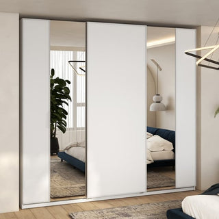 A modern bedroom features the CHOICEWARDROBE Madrid 220cm 3 Door Sliding Mirrored Wardrobe in high gloss white, reflecting a bed, hanging lamp, plant, and window with sheer curtains—sleek contemporary style with shelves and hanging rails.