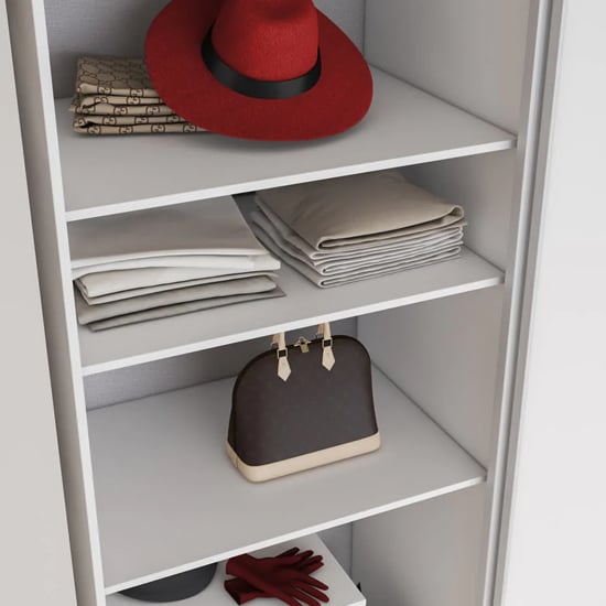 White sliding wardrobe interior with red hat, folded clothes, handbag, and gloves