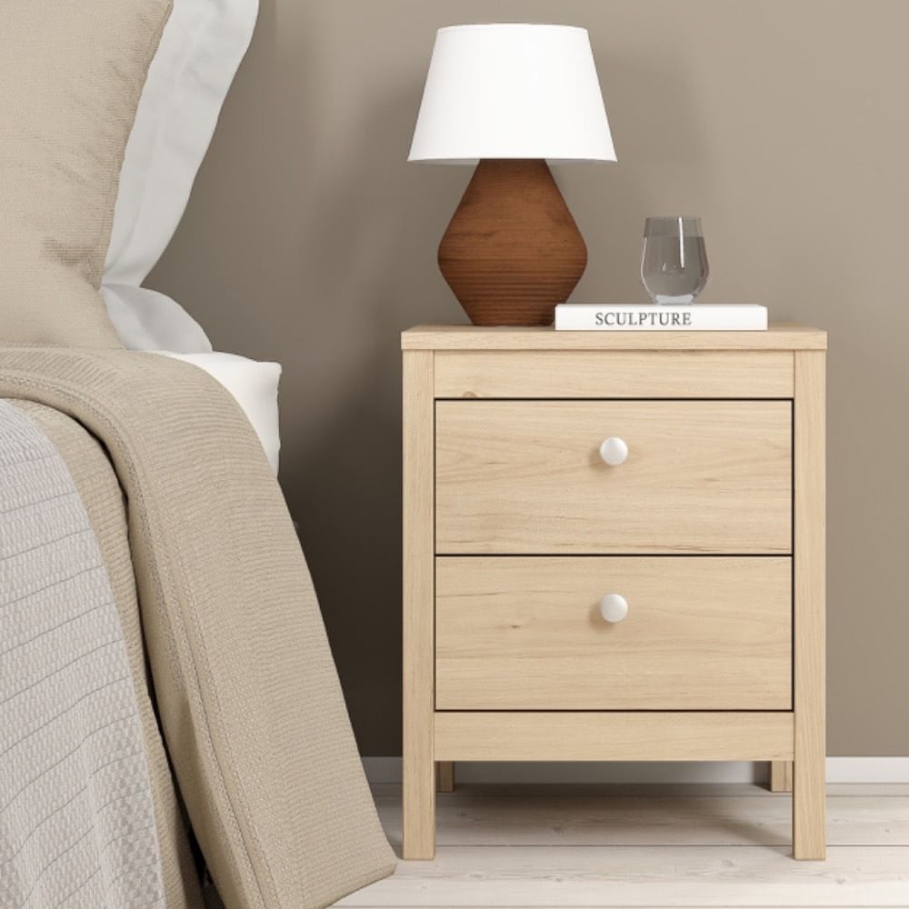 CHOICEWARDROBE Malibu oak effect bedside table with 2 drawers, minimalist design, next to bed with lamp & book.