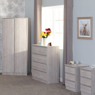 A bedroom features the CHOICEWARDROBE McGowan 4 Piece Set in Urban Snow finish—2 door wardrobe, 4 drawer chest, and 2 bedside tables. Beige curtains frame the window, with a deer picture on the wall for decor.