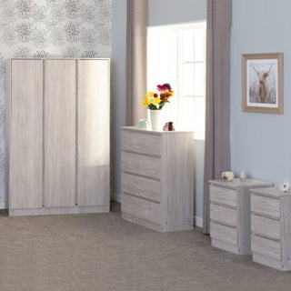A bedroom featuring the CHOICEWARDROBE McGowan Bedroom Furniture Set in Urban Snow finish—includes a modern 3 door wardrobe, 4 drawer chest with a vase of flowers, and 2 bedside tables. Beige curtains and deer artwork add to the décor.