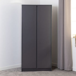 The CHOICEWARDROBE McGowen 2 Door Wardrobe in 80cm matt graphite grey features a minimalist modern design with a hanging rail and top shelf storage, providing compact organization against a white wall by the window.