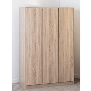 The CHOICEWARDROBE McGowen 3 Door Wooden Wardrobe in Sonoma Oak Finish, 115cm wide, features a modern design with a light finish, hanging rail, and shelves. It stands against a white wall on a grey carpeted floor.