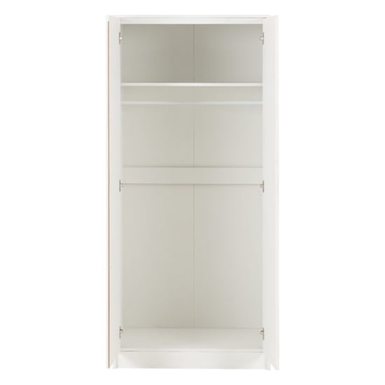 Interior of white two-door wardrobe with hanging rail and storage shelf