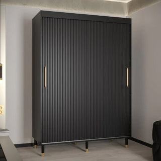 The CHOICEWARDROBE Millwall 150cm Black Ribbed Wardrobe has 2 sliding doors with gold handles, offering modern minimalist bedroom storage against a light wall and wood floor. Gold-tipped legs complete its stylish look.