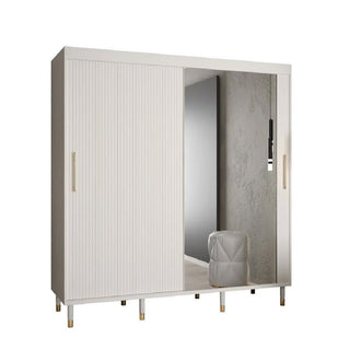 The CHOICEWARDROBE Millwall 200cm White Mirrored 2 Door Sliding Wardrobe features a ribbed panel design, gold handles, and spacious luxury storage, complementing this modern bedroom’s gray wall and white ottoman.
