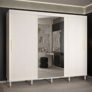 The CHOICEWARDROBE Millwall 250cm 3 Door Mirrored Sliding Wardrobe in white ribbed finish with gold handles features a large middle mirror reflecting a desk, chair, and shelves. This luxury modern wardrobe stands on six legs.
