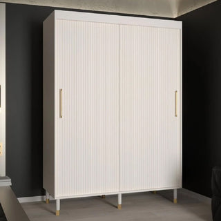 The CHOICEWARDROBE Millwall 150cm sliding door wardrobe features a white finish, gold handles, and a ribbed panel design, offering elegant bedroom storage against a dark wall and light flooring in a modern room.
