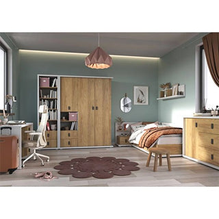 A tidy bedroom with light green walls features a bed, desk and chair, chest of drawers, shelves, and the CHOICEWARDROBE Minot Kids 2 Door Wooden Wardrobe in Oak & White Finish for storage. A brown floral rug and modern pendant light decorate the space.