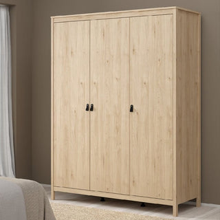 The CHOICEWARDROBE Nahlia Oak Wooden Wardrobe, a 3-door wardrobe with sleek black handles, stands against a taupe bedroom wall, complemented by a bed and sheer curtain for modern Scandinavian storage style.