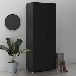 The CHOICEWARDROBE Nairo Black 2 Door Wardrobe with a minimalist matte finish and metal handles stands by a light wall, complemented by a round black mirror, potted plant, brown boots, and a textured storage basket.