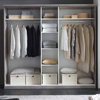 The CHOICEWARDROBE Namilon 236cm 4 Door LED Mirrored Wardrobe in Concrete Grey & White Gloss displays hanging shirts, jackets, and sweaters. Shelves hold folded towels, pillows, storage boxes below, and round containers on the top shelf.