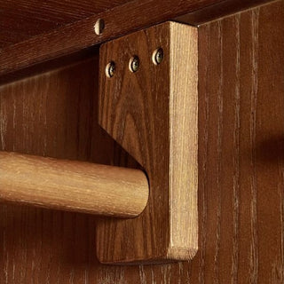 A close-up of a CHOICEWARDROBE Nestor Cherry Wood Wardrobe's bracket, fixed to the wood wall with three screws, firmly supporting a cylindrical wooden rod in this 2 Door, Mid-Century Modern Retro Style wardrobe with drawer.