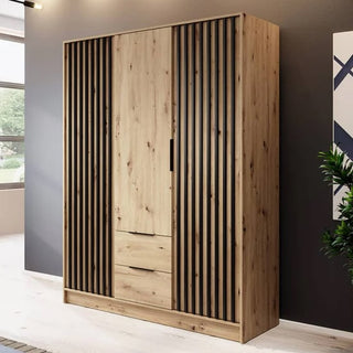 The CHOICEWARDROBE Newberry Wooden Wardrobe in Artisan Oak features three hinged doors, a modern slatted design, drawers, and full interior storage shelves—perfect for adding style and functionality to any bright, modern room.