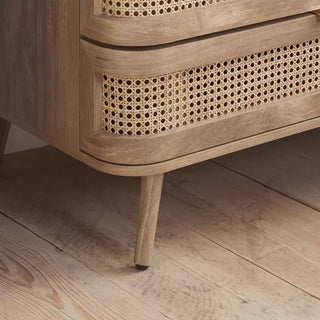 A close-up of the CHOICEWARDROBE Nixa Oak Rattan Wooden Wardrobe—90 cm, 2 doors, 1 drawer—with boho Scandi design, cane front panels, and solid wood legs on a light wooden floor, perfect for stylish bedroom storage.