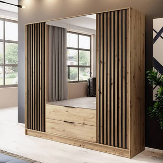 The CHOICEWARDROBE Norco 206cm Oak Effect 4 Door Wardrobe, featuring two full mirrored doors, slatted side panels, and two drawers, stands in a modern, well-lit room with large windows.
