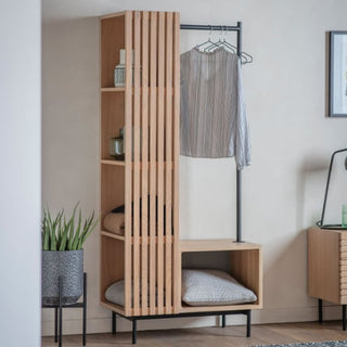The CHOICEWARDROBE Okonma Wooden Open Wardrobe features a natural oak slatted design, open shelves, and a hanging rail. Perfect for modern hallways or bedrooms, it offers stylish storage and display options, complemented by decor accents and greenery.