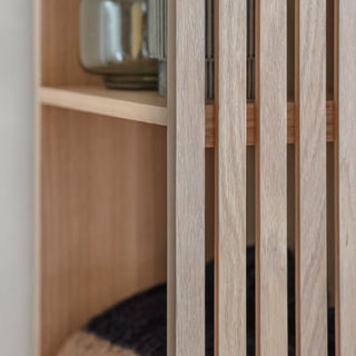 Close-up of the CHOICEWARDROBE Okonma Wooden Open Wardrobe featuring natural oak slatted design. A glass jar and dark cushion edge peek through the vertical slats, creating a minimal, tidy look ideal for modern hallway or bedroom storage.