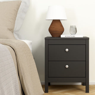 The CHOICEWARDROBE Oslo 3 Piece Bedroom Furniture Set in black includes a wardrobe, chest of drawers, and a matching bedside table placed by the bed made up with beige bedding. On the table are a lamp, glass of water, and the book Sculpture.