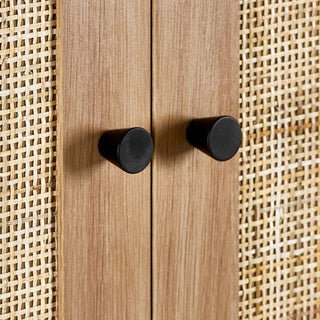 Close-up of two black knobs on the CHOICEWARDROBE Pabla 2 Door 1 Drawer Wooden Wardrobe (80cm Oak Finish), showcasing its rattan-style front and black metal base for a natural look.