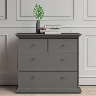 The CHOICEWARDROBE Parayo 3 Piece Bedroom Furniture Set in charcoal grey, featuring a 3-drawer chest, stands against a white paneled wall. On top are a dark vase with greenery, two stacked books, and magazines over light wood flooring.