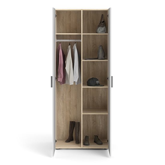 White 2-door wardrobe with oak-effect interior, showing hanging clothes, boots, bags, and a hat.
