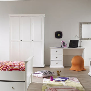 A bedroom with a white bed, colorful swirl-patterned bedspread, CHOICEWARDROBE Paroya Wooden Triple Door 140cm Wardrobe in White, white desk with a laptop, orange ball chair, wall clock, large mirror, and pillows on a light wood floor.