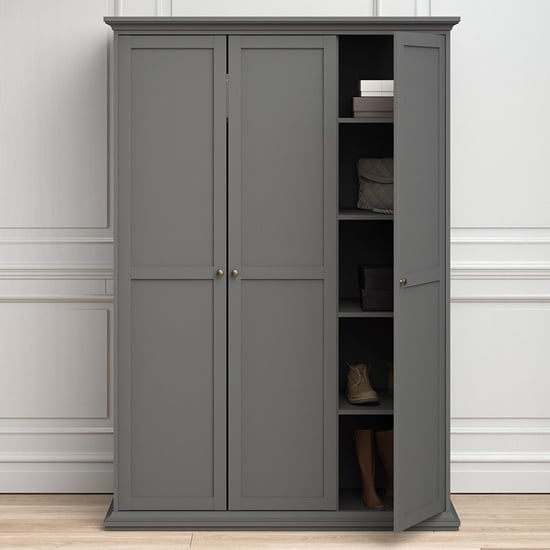 Grey 3 door wooden wardrobe with paneled detailing and brass knob handles, one door ajar.