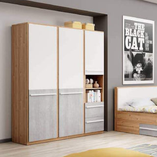 The CHOICEWARDROBE Peoria 3 Door Wardrobe in White & Concrete with an oak frame, 2 drawers, and open shelf storage stands beside a bed with yellow and white bedding; nearby, a shelf holds books and a "The Black Cat" poster hangs on the wall.