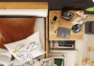 A CHOICEWARDROBE Peoria Sonoma Oak & White Small Double Bed with dinosaur-themed pillows sits by a nightstand holding headphones, a lamp, a notebook, music player, and stationery; books are stored on the shelf below.