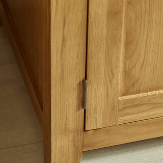 Close-up of the CHOICEWARDROBE Mabli 97 cm 2 Door Waxed Oak Wardrobe’s solid wooden frame, showing its metal hinge and classic shaker design. The wardrobe sits on a light-colored floor.