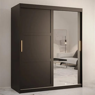 The CHOICEWARDROBE Rieti 2 Door Mirrored Sliding Wardrobe in 150cm matt black with gold handles and full-length mirror stands on a marble floor in a striped room, reflecting a sofa and lamp in its modern panelled design.