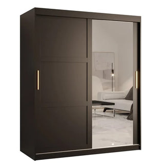 The CHOICEWARDROBE Rieti 2 Door Mirrored Sliding Wardrobe in matt black, with gold handles, modern panelled design, and a full-length mirror, adds elegance to a minimalist light-colored bedroom.