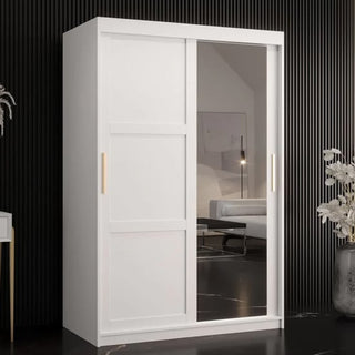 The CHOICEWARDROBE Rieti Mirrored 2 Door Sliding Wardrobe features a modern white panel design with gold handles, a full-length mirror, and spacious storage, standing stylishly against a dark, striped wall and reflecting the room's décor.